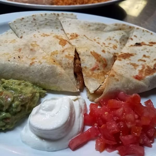 San Diego's Mexican Grill quesadilla with guacamole, sour cream, and diced tomatoes on a white plate.