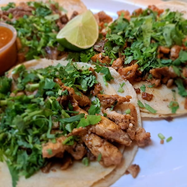 Close-up of three San Diego's Mexican Grill tacos with meat, cilantro, and a lime wedge.