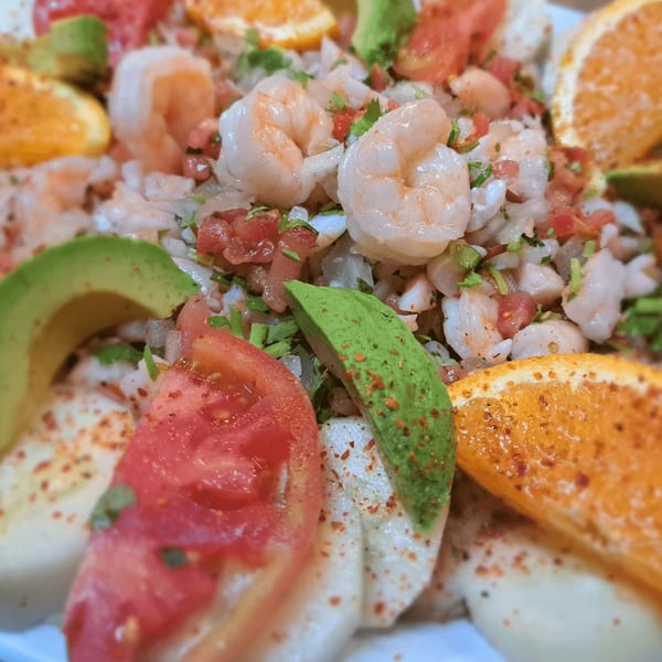 Close-up of Mexican shrimp ceviche with avocado, tomatoes, and orange slices.
