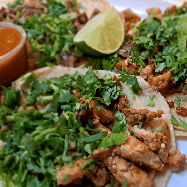 Close-up of San Diego's Mexican Grill tacos with meat, cilantro, and a lime wedge.